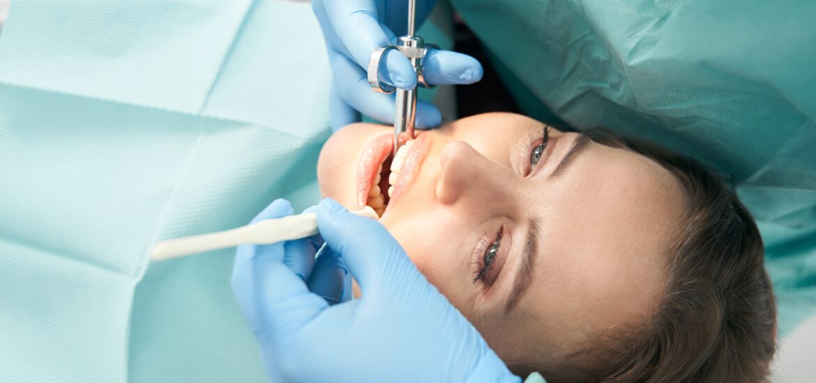 dentist in blue gloves numbing a patient before a root canal